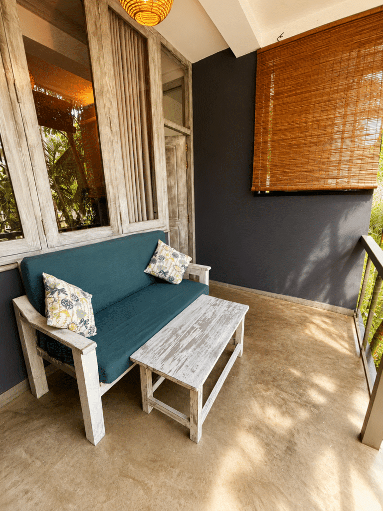 Private balcony with a cushioned bench, bamboo blind and a deep-blue accent wall at Salt House, Hiriketiya Bay, Sri Lanka